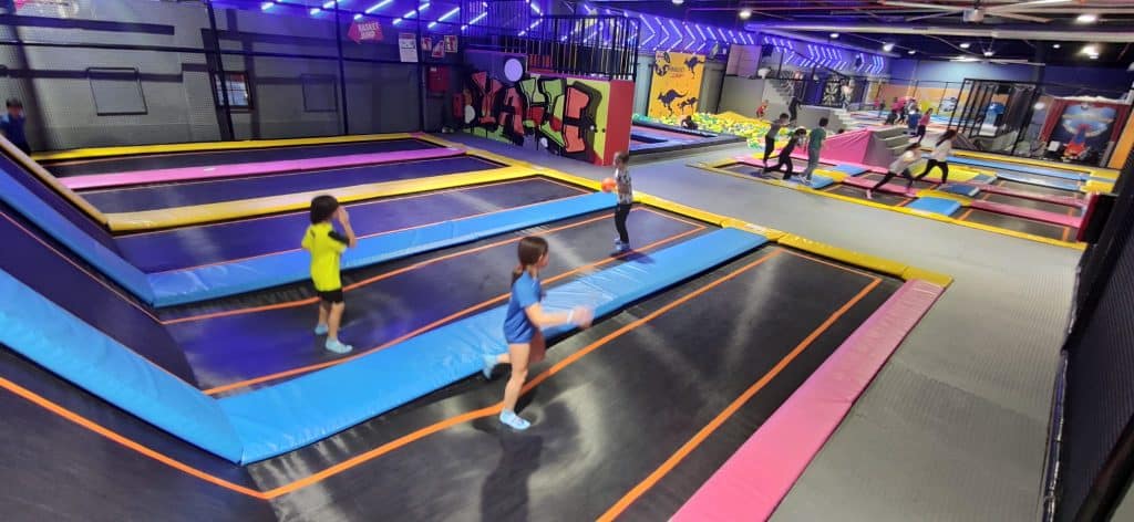 Niños juegan en parque infantil y de colchonetas